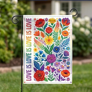 May include: A rectangular garden flag featuring a white background with a vibrant floral pattern in red, orange, yellow, blue, and purple. The text LOVE IS LOVE IS LOVE IS LOVE is printed vertically in rainbow colors along the left side.