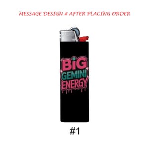 May include: A black lighter with the text "BIG GEMINI ENERGY" in pink and teal, with dripping accents. The lighter has a silver top and a red ignition button. The number "#1" is at the bottom.