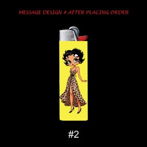 May include: A yellow lighter featuring a cartoon illustration of a woman in a polka dot dress. The lighter has the text "MESSAGE DESIGN # AFTER PLACING ORDER" and the number "#2" on it.