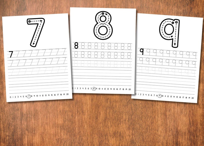 May include: Three white sheets of paper with black numbers 7, 8, and 9, each with dotted lines for tracing and practice lines below. The sheets are on a wooden surface, ideal for educational activities.