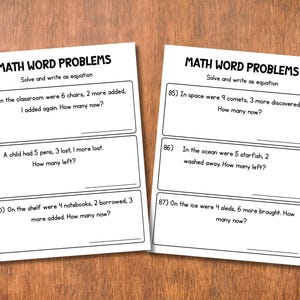 May include: Two white worksheets with math word problems on a wooden surface. The worksheets have the title "MATH WORD PROBLEMS" and include several addition and subtraction problems. The problems are numbered and have space for answers.