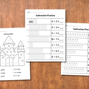 May include: Three white sheets of paper with math practice problems and a color-by-number castle illustration. The subtraction practice sheets have problems with visual aids. The color-by-number sheet has a castle and color key.