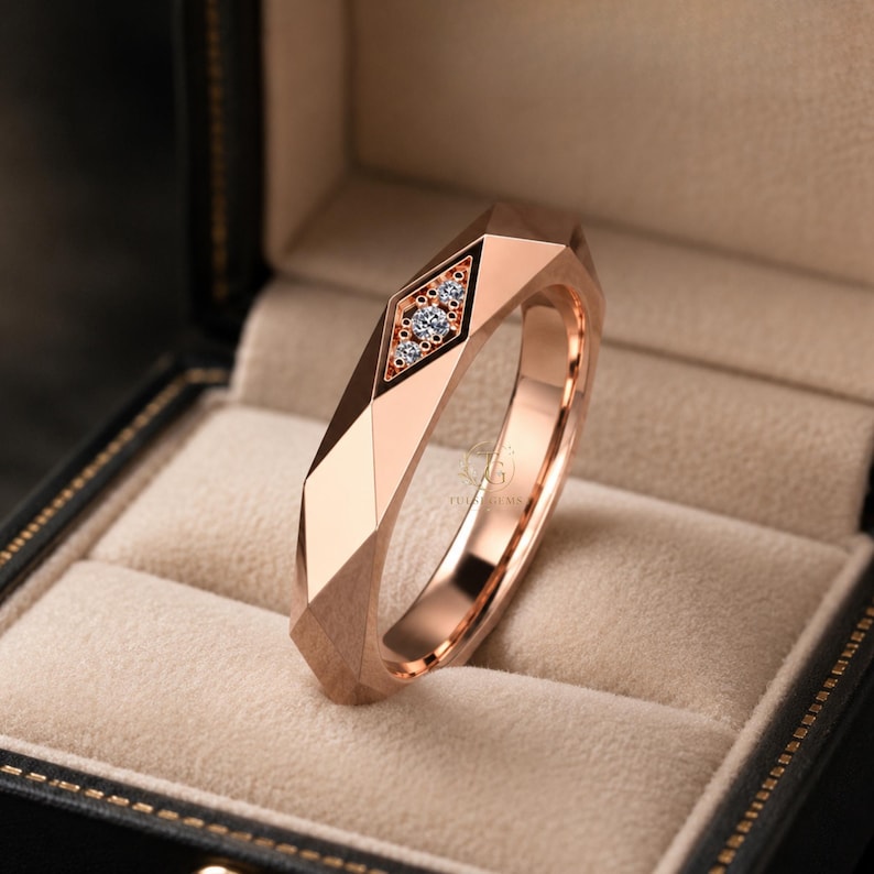 Modern geometric rose gold band ring featuring angular faceted detailing with small round lab grown diamonds set in a central geometric bezel design. Close-up luxury jewelry photo highlights the polished faceted finish, contemporary minimalist craftsmanship, elegant stacking ring style, and refined modern wedding band aesthetic perfect for everyday luxury wear and designer jewelry collections.