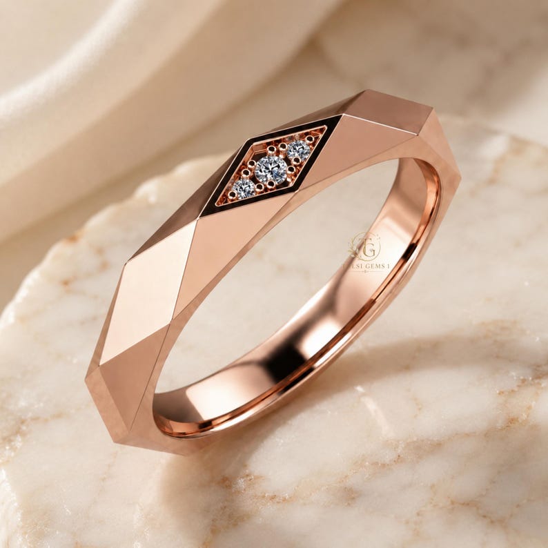Modern geometric rose gold band ring featuring angular faceted detailing with small round lab grown diamonds set in a central geometric bezel design. Close-up luxury jewelry photo highlights the polished faceted finish, contemporary minimalist craftsmanship, elegant stacking ring style, and refined modern wedding band aesthetic perfect for everyday luxury wear and designer jewelry collections.