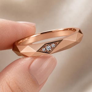 Modern geometric rose gold band ring featuring angular faceted detailing with small round lab grown diamonds set in a central geometric bezel design. Close-up luxury jewelry photo highlights the polished faceted finish, contemporary minimalist craftsmanship, elegant stacking ring style, and refined modern wedding band aesthetic perfect for everyday luxury wear and designer jewelry collections.