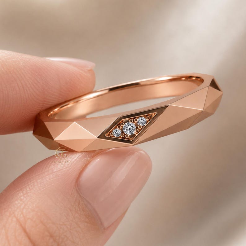 Modern geometric rose gold band ring featuring angular faceted detailing with small round lab grown diamonds set in a central geometric bezel design. Close-up luxury jewelry photo highlights the polished faceted finish, contemporary minimalist craftsmanship, elegant stacking ring style, and refined modern wedding band aesthetic perfect for everyday luxury wear and designer jewelry collections.
