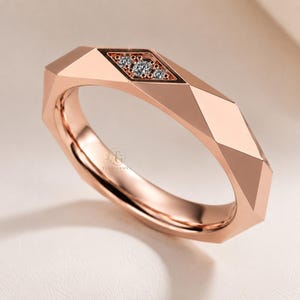 Modern geometric rose gold band ring featuring angular faceted detailing with small round lab grown diamonds set in a central geometric bezel design. Close-up luxury jewelry photo highlights the polished faceted finish, contemporary minimalist craftsmanship, elegant stacking ring style, and refined modern wedding band aesthetic perfect for everyday luxury wear and designer jewelry collections.