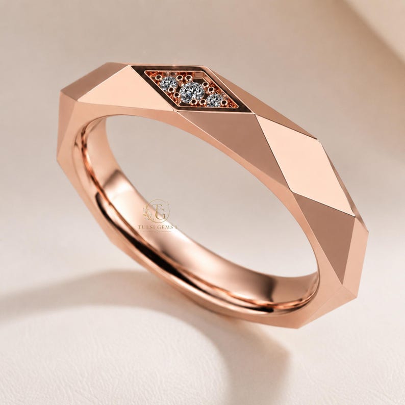 Modern geometric rose gold band ring featuring angular faceted detailing with small round lab grown diamonds set in a central geometric bezel design. Close-up luxury jewelry photo highlights the polished faceted finish, contemporary minimalist craftsmanship, elegant stacking ring style, and refined modern wedding band aesthetic perfect for everyday luxury wear and designer jewelry collections.