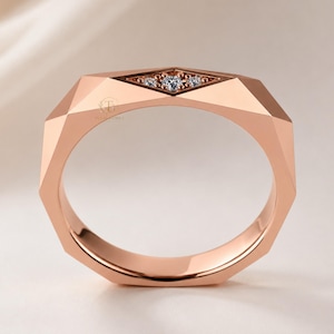 Modern geometric rose gold band ring featuring angular faceted detailing with small round lab grown diamonds set in a central geometric bezel design. Close-up luxury jewelry photo highlights the polished faceted finish, contemporary minimalist craftsmanship, elegant stacking ring style, and refined modern wedding band aesthetic perfect for everyday luxury wear and designer jewelry collections.