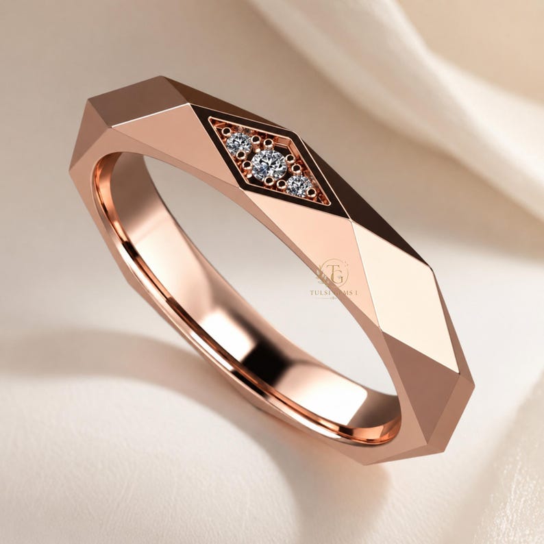Modern geometric rose gold band ring featuring angular faceted detailing with small round lab grown diamonds set in a central geometric bezel design. Close-up luxury jewelry photo highlights the polished faceted finish, contemporary minimalist craftsmanship, elegant stacking ring style, and refined modern wedding band aesthetic perfect for everyday luxury wear and designer jewelry collections.