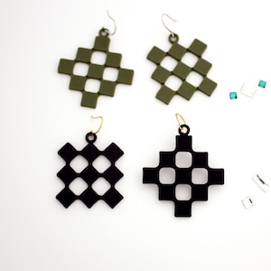 May include: Four pairs of geometric drop earrings. Two pairs are olive green, and two are black. Each earring features a woven square design with a hook closure. Small, square, iridescent embellishments are scattered around the earrings.