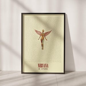 May include: A framed poster featuring a cream-colored background filled with dense, small black text. Centered is an anatomical figure with large, detailed wings. At the bottom, the text NIRVANA IN UTERO is printed in bold, dark red capital letters.