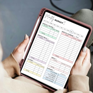 May include: A digital monthly budget planner displayed on a tablet. The planner features sections for income, expenses, bills, debts, savings, and a summary. The tablet is held in a pink case, with a stylus resting on the side. The text "Monthly BUDGET" is visible.