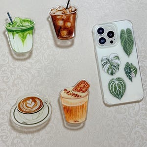 May include: A white ceramic mug with a black handle and the text "But First, Coffee" in a bold, black font. The mug is sitting on a wooden surface. The mug is approximately 4 inches tall.