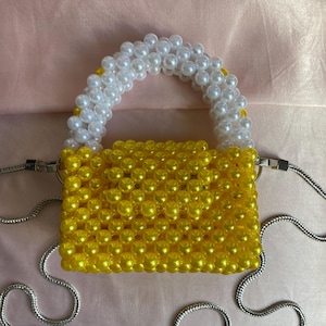 Puede incluir: Una taza de cerámica blanca con un asa negra y el texto "But First, Coffee" en negrita negra. La taza se encuentra sobre un fondo neutro, resaltando su diseño sencillo.