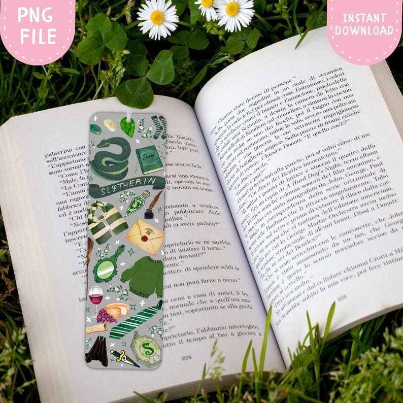 Op de afbeelding: Een grijze boekenlegger met groene illustraties, waaronder een slang en een trui. Het woord "Slytherin" staat op een banner. De boekenlegger ligt op een open boek met tekst.