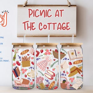 May include: Three glass tumblers with wooden lids and straws, decorated with picnic-themed illustrations. A sign above reads "Picnic at the Cottage." The tumblers feature images of bread, strawberries, and picnic baskets. The picture size is 9.84 x 5.12 inches (25x13 cm).