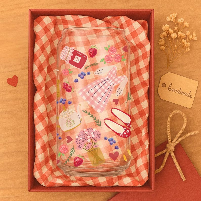 May include: A clear glass can-shaped tumbler with a whimsical design featuring a pink gingham dress, strawberries, roses, and a jar of jam. The tumbler is presented in a red box with a red and white checkered lining, and a "handmade" tag.
