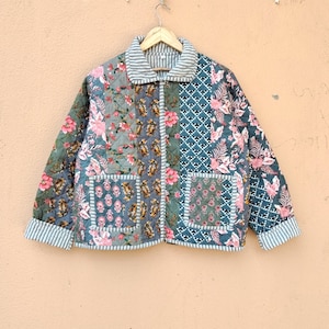 May include: A quilted jacket featuring a patchwork design with various floral and geometric patterns in shades of green, pink, and blue. The jacket has a striped collar and cuffs, a front button closure, and two square patch pockets on the front.