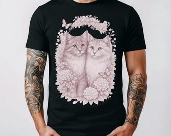 Könnte beinhalten: Schwarzes T-Shirt mit einer detaillierten Illustration von zwei flauschigen Katzen, umgeben von Blumen und Schmetterlingen. Das Kunstwerk ist in sanften Rosa- und Weißtönen gehalten und schafft ein zartes und charmantes Design. Die Katzen sind der Mittelpunkt des Designs.