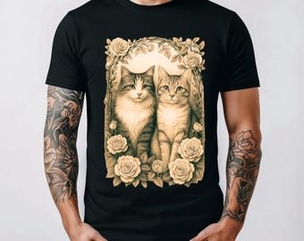 Könnte beinhalten: Schwarzes T-Shirt mit einer sepiafarbenen Illustration von zwei Katzen, umgeben von Rosen. Die Katzen haben detailliertes Fell und sind in einem floralen Bogen zentriert. Die Rosen blühen voll, was eine Vintage-Ästhetik verleiht.