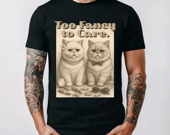 Könnte beinhalten: Schwarzes T-Shirt mit einem Sepia-farbenen Motiv von zwei Perserkatzen, die mit Accessoires geschmückt sind, und dem Text "Too Fancy to Care." Die Katzen sind von Make-up und Sonnenbrillen umgeben.
