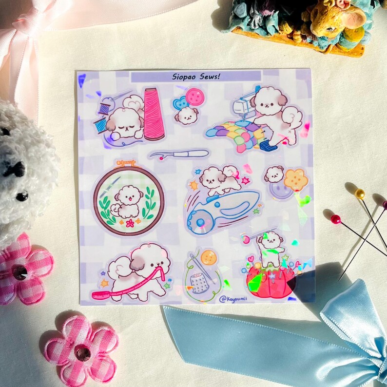 May include: A sheet of stickers featuring cartoon poodles and sewing-themed illustrations. The stickers include images of thread spools, sewing machines, embroidery hoops, and buttons. The text "Siopao Sews!" is visible at the top of the sheet.