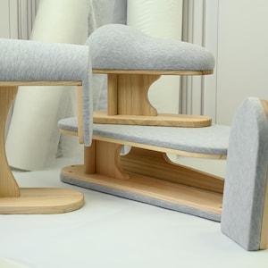 May include: A set of wooden tailor's tools, including a sleeve board, pressing ham, and a curved pressing surface. The tools have light gray padded surfaces and are made of natural-colored wood.