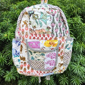 Op de afbeelding: Gewatteerde rugzak met een patchwork ontwerp met bloemen-, tijger- en geometrische patronen in verschillende kleuren. De rugzak heeft een voorvak, zijvakken en een zwart-wit gestreepte rand. Hij heeft een handvat aan de bovenkant en verstelbare bandjes.