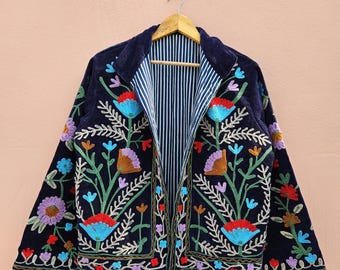 May include: A navy blue embroidered jacket with a floral design. The jacket features colorful flowers in red, blue, purple, and orange, with green leaves and white accents. The inside lining is striped in white and blue.