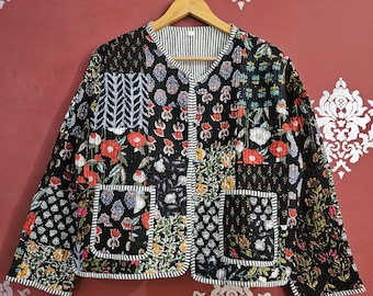 May include: A black quilted jacket with a floral patchwork design. The jacket features a V-neck, two front pockets, and a striped lining. The jacket is hanging on a wooden hanger.