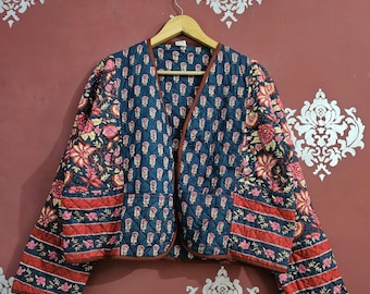 Könnte beinhalten: Gesteppte Jacke mit marineblauem Hintergrund und einem Blumenmuster in Rosa und Rot. Die Jacke hat einen V-Ausschnitt und ist mit einem braunen Rand versehen. Die Ärmel und der untere Saum weisen ein rot-blaues Streifendesign auf.