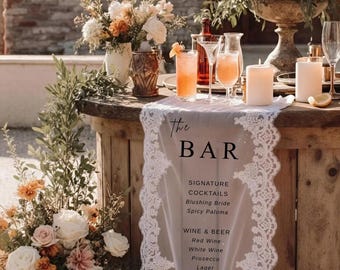 May include: A rustic bar setup with floral arrangements, cocktails, and a menu. The menu lists signature cocktails, wine, beer, spirits, and non-alcoholic beverages. A white lace runner displays the bar's offerings.