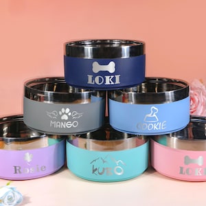 May include: A collection of stainless steel pet bowls in various colors, including blue, gray, light blue, pink, purple, and teal. Each bowl features a silver rim and a personalized name or design, such as a bone, paw prints, or mountains. The bowls are designed for pets.