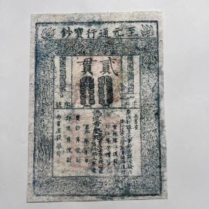 Peut inclure: Un ancien billet de banque chinois avec une calligraphie complexe et des motifs ornés. Le papier a un aspect texturé et vieilli, avec de l'encre bleue et noire délavée. Le texte comprend les mots "Billet de trésorerie" et "Deux chaînes de pièces".