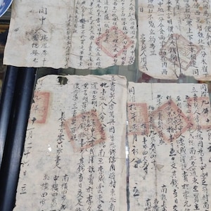 May include: Several sheets of aged paper covered in Chinese calligraphy and red seals. The paper is yellowed and worn, indicating age. The text is densely packed in vertical columns. The documents appear to be historical, possibly legal or administrative.