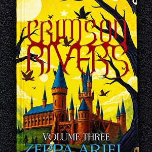 Può includere: Un libro con copertina rigida intitolato Crimson Rivers Volume Three di Zeppa Ariel. La copertina raffigura un grande castello marrone con tetti blu su un cielo giallo brillante, circondato da sagome di alberi scuri, uccelli in volo e un sentiero rosso.