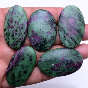 May include: Five oval-shaped gemstones with a polished finish. The stones feature a mix of green, dark red, and black colors. The gemstones are smooth and appear to be natural, with unique patterns and variations in color.