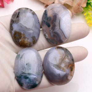 Può includere: Quattro pietre preziose ovali con superficie lucida. Le pietre presentano un mix di colori grigio, bianco, marrone e verde, con motivi e venature unici. Queste pietre naturali sono probabilmente utilizzate per gioielli o artigianato.