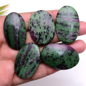 May include: Five polished oval cabochons of zoisite with ruby inclusions, displaying a mottled pattern of deep forest green, vibrant magenta, and black speckles. Each stone has a smooth, glossy surface and a distinct, natural color variation.
