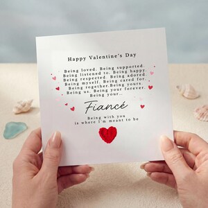May include: A Valentine's Day card with the message "Happy Valentine's Day" and a list of sentiments. The card features the word "Fiancé" and the phrase "Being with you is where I'm meant to be." A red heart is at the bottom.