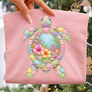 May include: A pink fabric item featuring a colorful turtle design. The turtle has a patchwork-style shell with various colors and patterns. The center of the turtle's shell has a blue and white checkered pattern with flowers and coral.