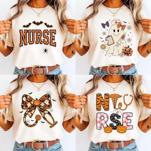 Puede incluir: Cuatro camisetas color crema con diseños de enfermeras con temática de Halloween. Una camiseta presenta la palabra "NURSE" con murciélagos y una araña. Otra muestra una enfermera fantasma con una calabaza. La tercera tiene un lazo y un estetoscopio.