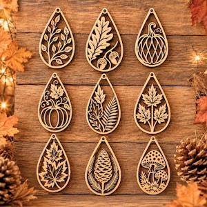 May include: Nine teardrop-shaped wooden cutouts featuring intricate laser-cut designs of autumn motifs including leaves, acorns, pumpkins, a pinecone, and mushrooms. Each piece has a small hole at the top for hanging as a decorative ornament.