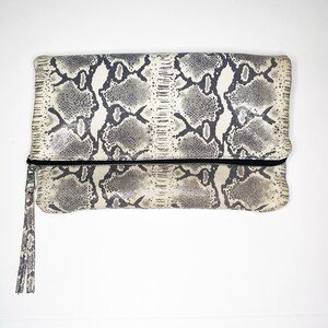 May include: A white and gray snakeskin clutch with a zipper closure and a tassel.
