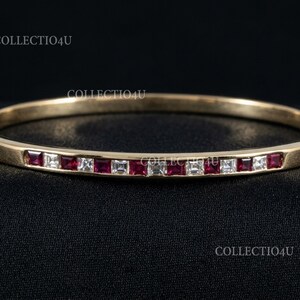 Pode incluir: Uma pulseira de ouro com pedras preciosas vermelhas e brancas quadradas alternadas. A pulseira tem um fecho de dobradiça e está colocada sobre um fundo preto. O texto "COLLECTION4U" é visível na imagem.