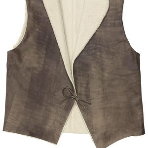 May include: A reversible vest with a brown exterior and a cream-colored, fuzzy interior. The vest has a tie closure at the front. The garment appears to be made of a soft material, suitable for layering. The vest is designed to be worn open.
