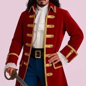 Puede incluir: Un abrigo de pirata de terciopelo rojo con ribetes y botones dorados. El abrigo tiene un cuello alto y mangas largas con puños dorados. El atuendo incluye una camisa blanca con volantes, pantalones azules, un cinturón negro y una espada.