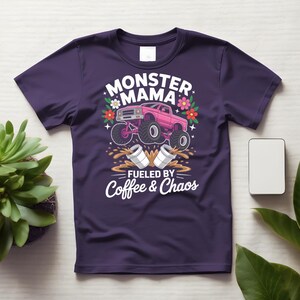 May include: A purple t-shirt featuring a pink monster truck graphic with the words "MONSTER MAMA" and "FUELED BY COFFEE & CHAOS". The design includes flowers and coffee cups.