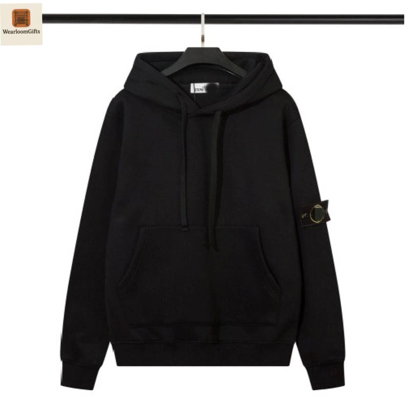 May include: A black hooded sweatshirt with a kangaroo pocket and a small patch on the left sleeve. The sweatshirt is hanging on a black hanger against a white background. The brand name "WearloomGifts" is in the top left corner.